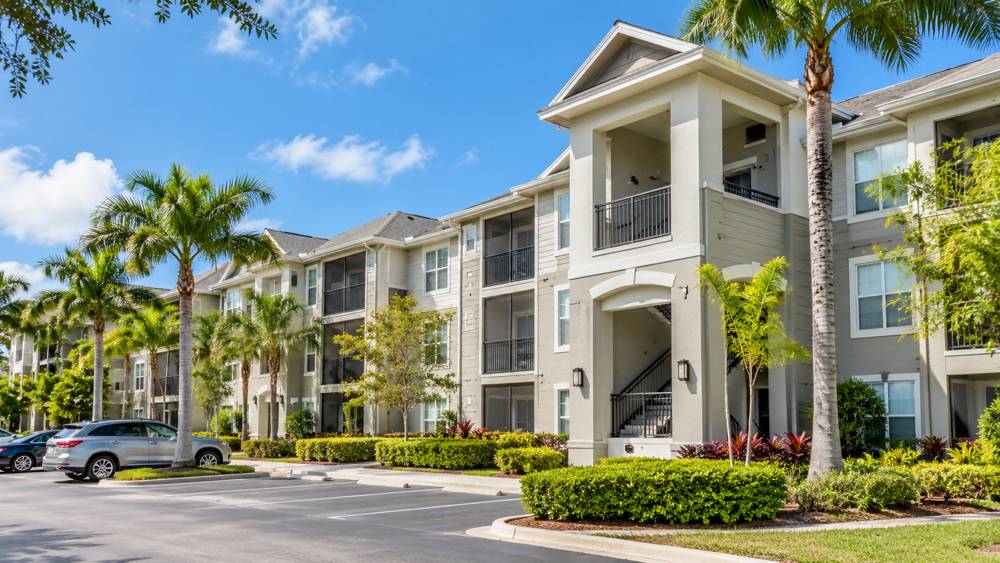 Three-story apartment building with palm trees and landscaping in Florida daylight
